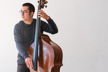 Professional double bass player. Photo shooting in studio. White background