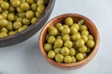 Two bowl full with marinated green olives on white background