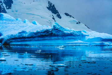 Fototapeta na wymiar Snowing Blue Iceberg Reflection Paradise Bay Skintorp Cove Antarctica