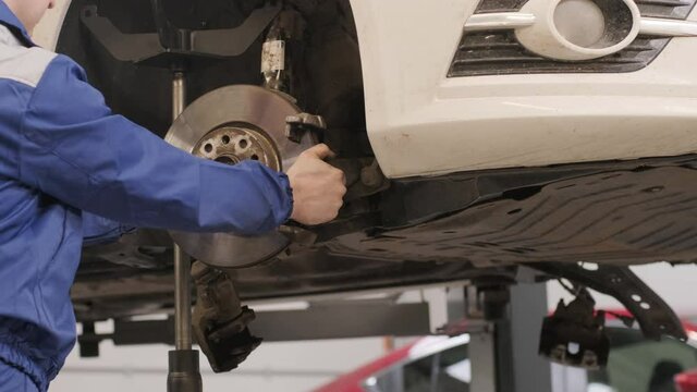 Car mechanic replacing car wheel brake shoes of lifted automobile at repair service station