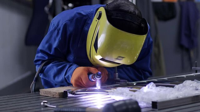 Man wearing mask welding in a workshop. Metal workers use manual labor. Skilled welder. Welder is welding the stainless steel pipes in the factory. welder Industrial part in factory.