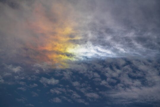 This photograph captures a cloudscape being illuminated by a vibrant rainbow.