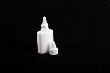 nasal drops white plastic  bottle, black background, cap off
