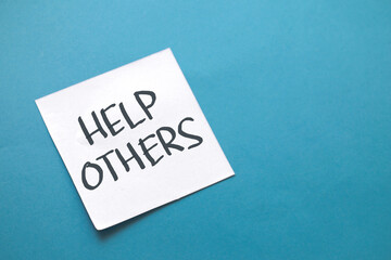 Help others, text words typography written on paper against blue background, life and business motivational inspirational