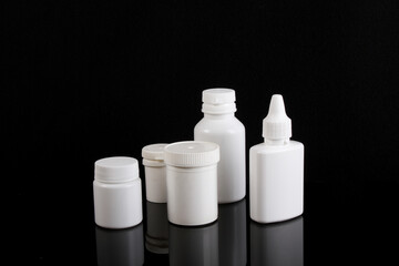 Multiple medicine bottles, black background reflection