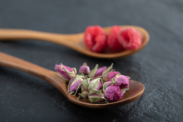 Budding roses and raspberries on wooden spoons