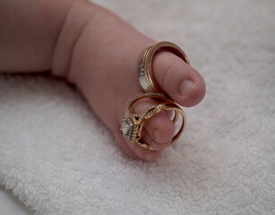 Wedding and engagement rings displayed on a babys toes