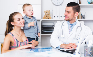 Portrait of man medical worker talking with young mother with child