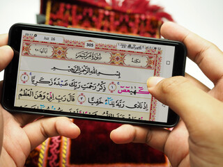 Man reading holy Quran on his smartphone after praying