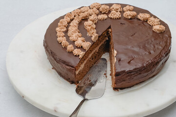 Chocolate cake with chocolate cream and chocolate ganache glaze close up on marble serving board