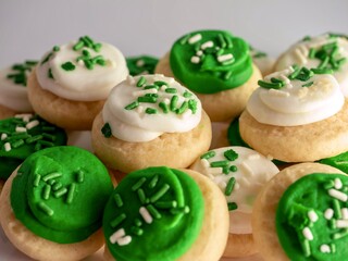 St Patrick’s Day holiday frosted sugar cookies with green and white frosting and sprinkles with four leaf clover shamrocks for a festive sweet treat.