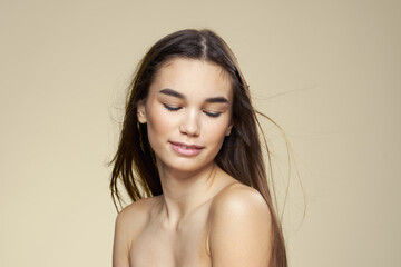 Obraz premium Pretty woman naked shoulders long hair body care beige background