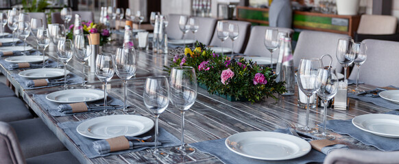 Modern veranda restaurant interior, flowers, banquet setting, glasses, plates