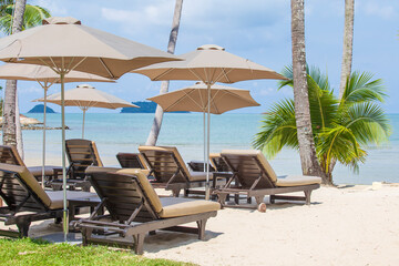 Relaxing beds and sun umbrella in tropical sand beach near sea