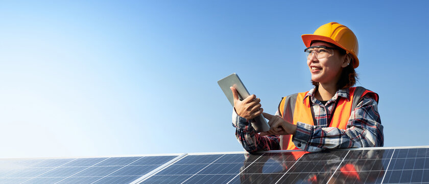 Female Electrical engineer holding a tablet with the solar panel outdoors.