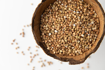 green buckwheat groats in coconut shell on white background close-up top view