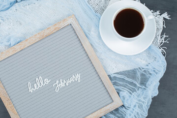 Hello february poster embedded on grey background with a cup of drink aside