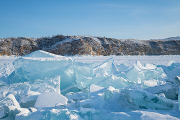 Beautiful blue ice spikes on the Frozen Lake with mountains on the background.