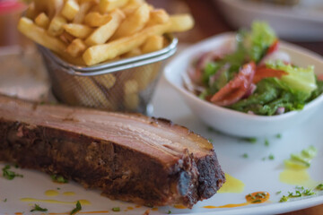 Delicious Ribs green salads and french fries on a white dish on table