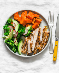 Balanced diet lunch - grilled turkey, boiled sweet potatoes, kale cabbage, avocado, cucumbers, radish salad on a light background, top view