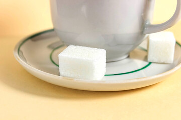 A mug on a saucer, with sugar cubes next to it.