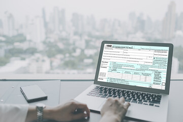 Tax concept, accountants are filling online tax information using a laptop.