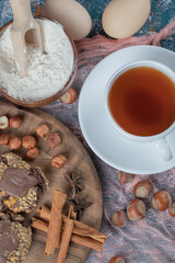 Chocolate nuts cookies on a wooden board served with cinnamons and a cup of tea