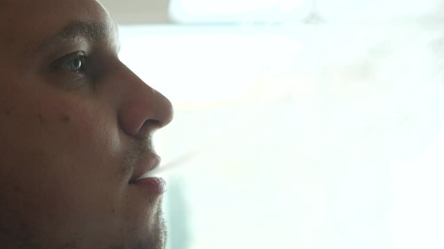 Close-up of man inhaling an e-cigarette vaping device. slow motion