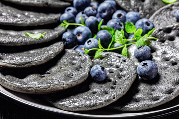 Obraz na płótnie Canvas black sweet pancakes served with berries and mint