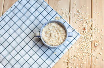 Fresh oatmeal porridge in a plate on a nice napkin and on the table