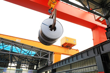 The crane lifts the rolled strip in the factory