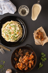 dinner with fried shrimps and pasta in white sauce, top view