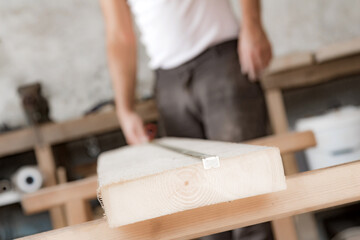 Male carpenter working with wood material in a garage.