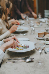 There is a salad close-up. hands properly hold cutlery in the restaurant. table etiquette.