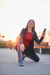 Modern young woman with cellphone making pause during jogging / exercise.