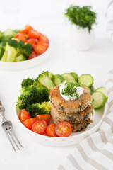 Vegetarian dish of potato patties with herbs and vegetables in a plate, close-up