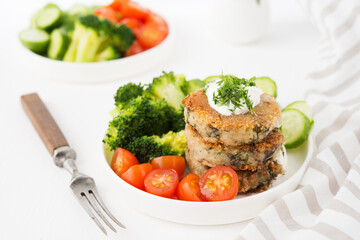 Vegetarian dish of potato patties with herbs and vegetables in a plate, close-up