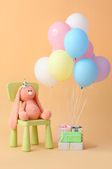 Air balloons with chair, toy and gifts on color background