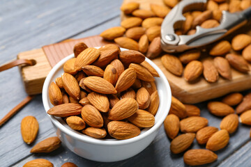 Bowl with tasty almonds on wooden background
