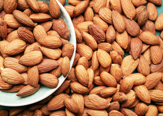 Plate with tasty almonds on table, closeup