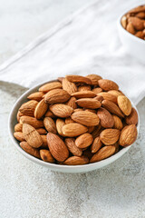 Bowl with tasty almonds on light background