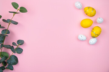 Naklejka na ściany i meble Happy easter concept. Yellow eggs and a branch of eucalyptus on a pink pastel background. Flat lay, top view, copy space.