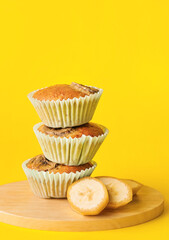 Tasty banana muffins on color background