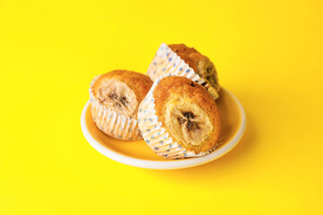 Plate with tasty banana muffins on color background