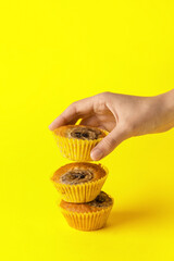 Female hand with tasty banana muffins on color background