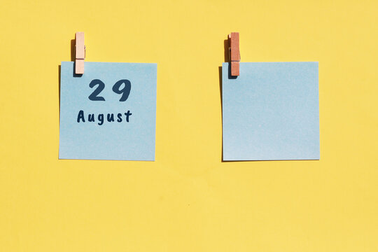 August 29. 29th day of the month, calendar date. Two blue sheets for writing on a yellow background. Top view, copy space. Summer month, day of the year concept