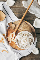 Bowl with tasty coconut chips on wooden background