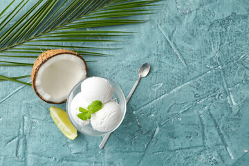Glass with tasty coconut ice cream on color background
