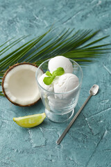 Glass with tasty coconut ice cream on color background