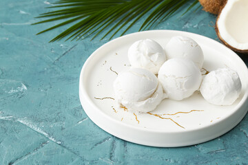 Plate with tasty coconut ice cream on color background